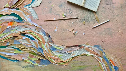 Buntes Papier-Collage auf Tisch mit offenem Buch.