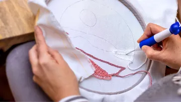Person stickt Stoff mit Punch-Needle-Werkzeug.