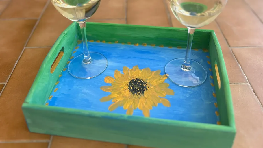 Wooden tray with sunflower, holding wine glasses.