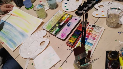 Aquarellmalerei mit Paletten auf Tisch.