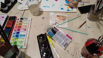 Kunstmaterialien auf Tisch, Hand malt Papier.
