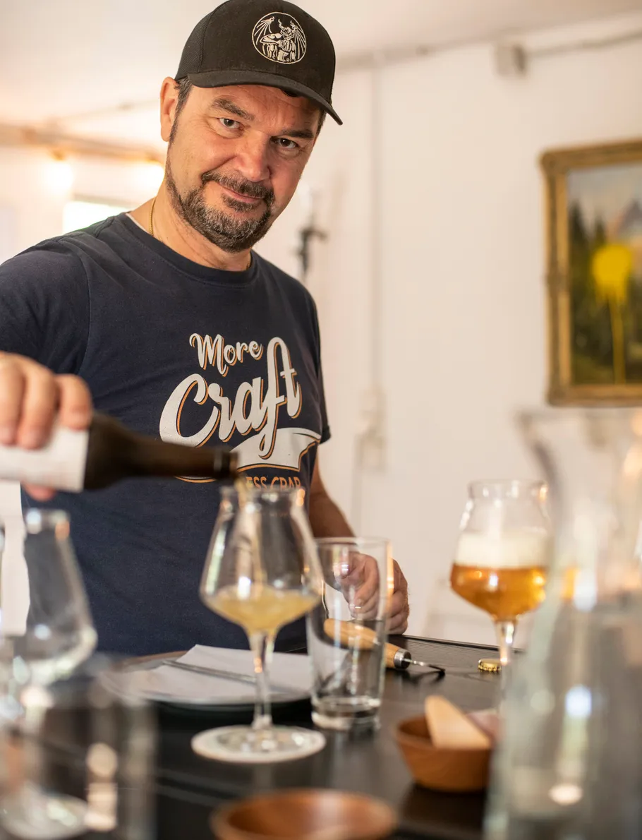 Mann gießt Getränk in Glas am Tresen.