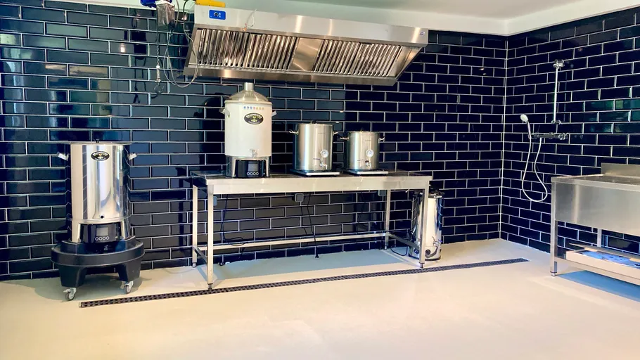 Commercial kitchen with brewing equipment and black tiles.