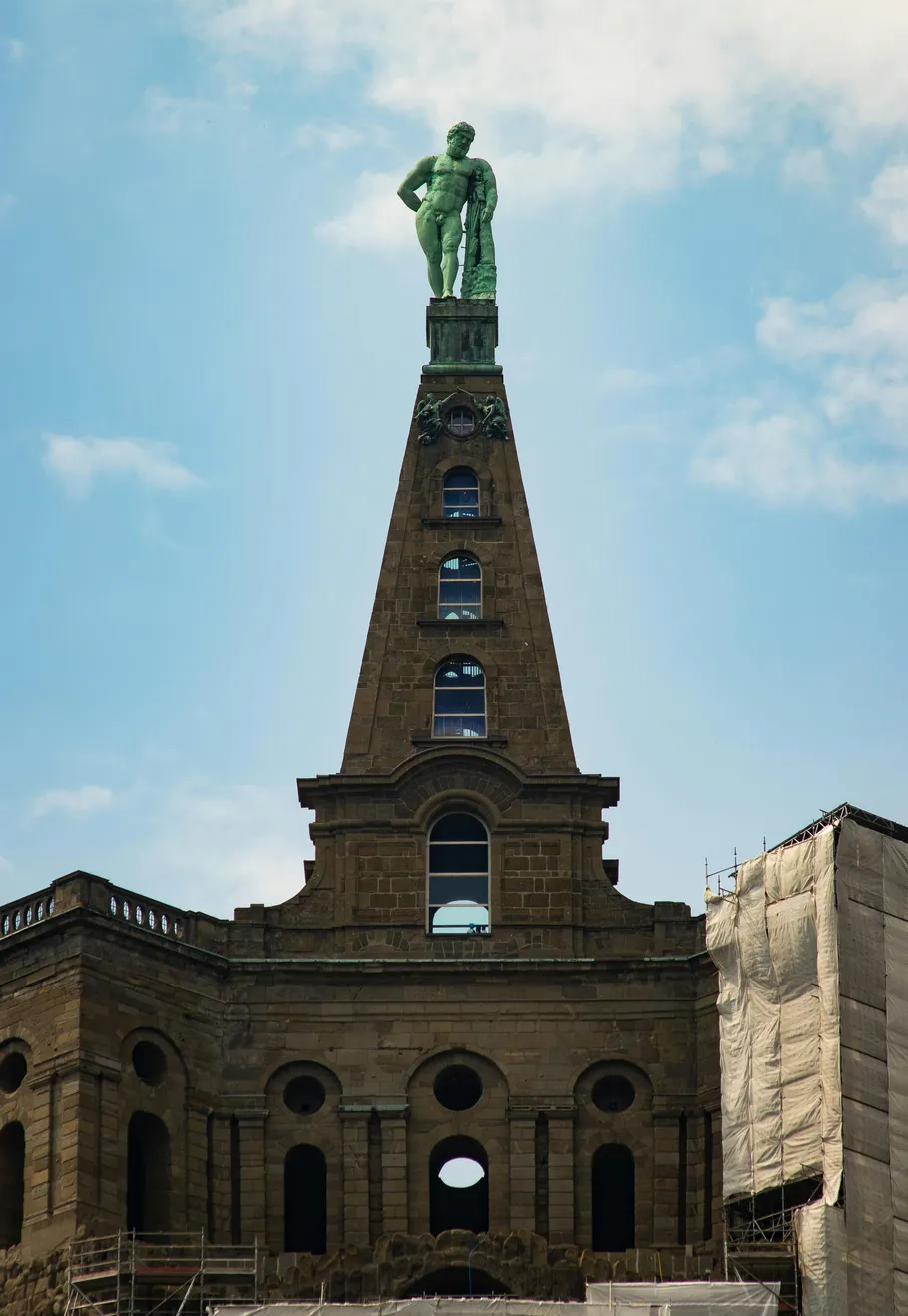 Statue auf hohem Gebäude mit Bogenfenstern.