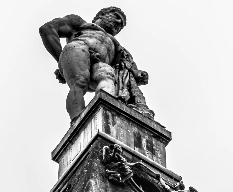 Hercules statue atop building against sky.