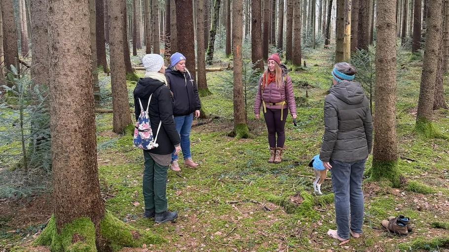 Vier Personen stehen in einer Waldlichtung.