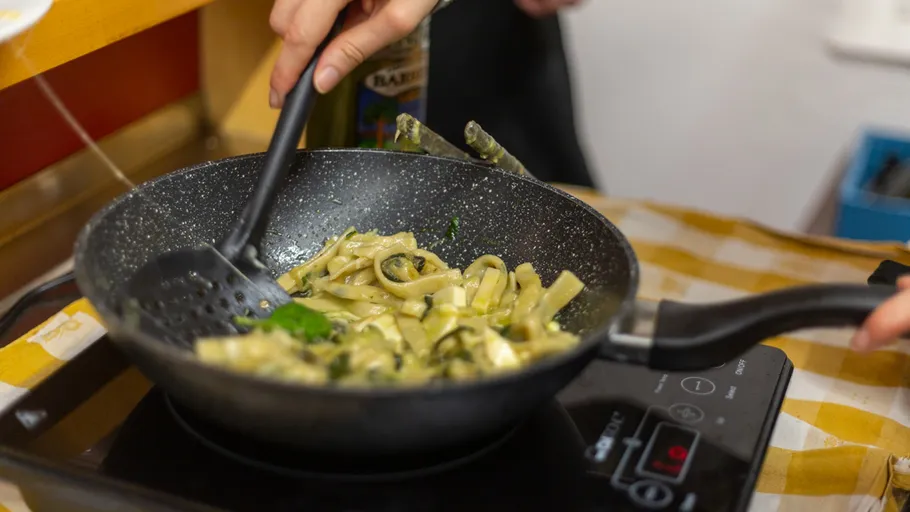 Person cooking pasta in a frying pan.