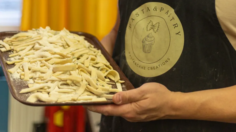 Person hält ein Tablett mit ungekochter Pasta.