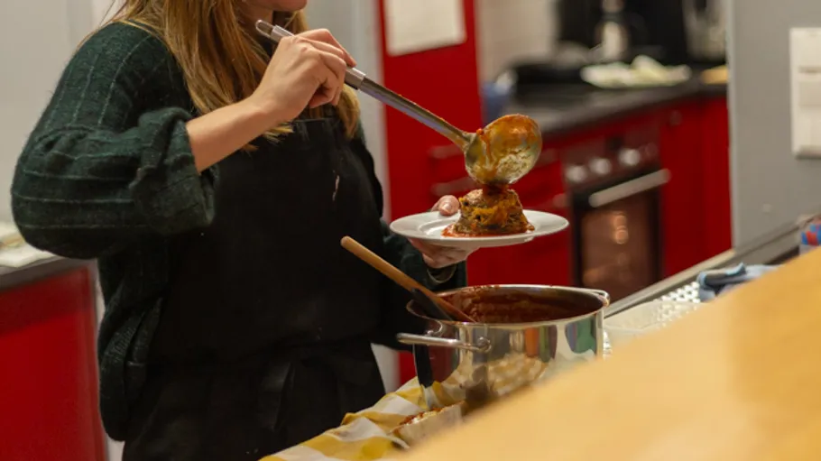 Person serving meal from pot in kitchen.