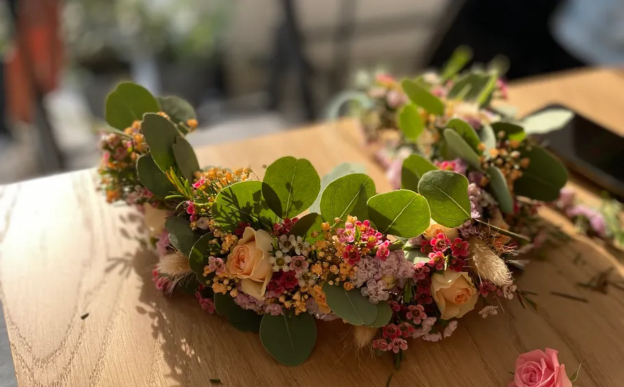 Blumenkranz mit Rosen auf Holztisch.