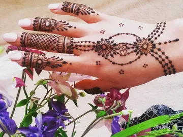 Hand mit Henna-Muster umgeben von bunten Blumen.