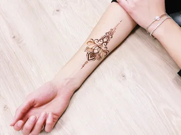 Henna-Tattoo auf dem Unterarm, liegt auf einem Holztisch.