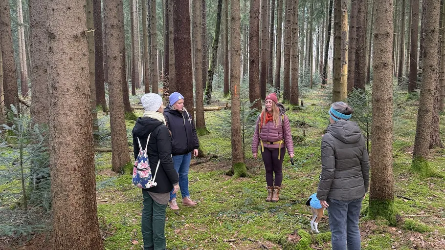 Fünf Personen stehen in einer Waldlichtung.