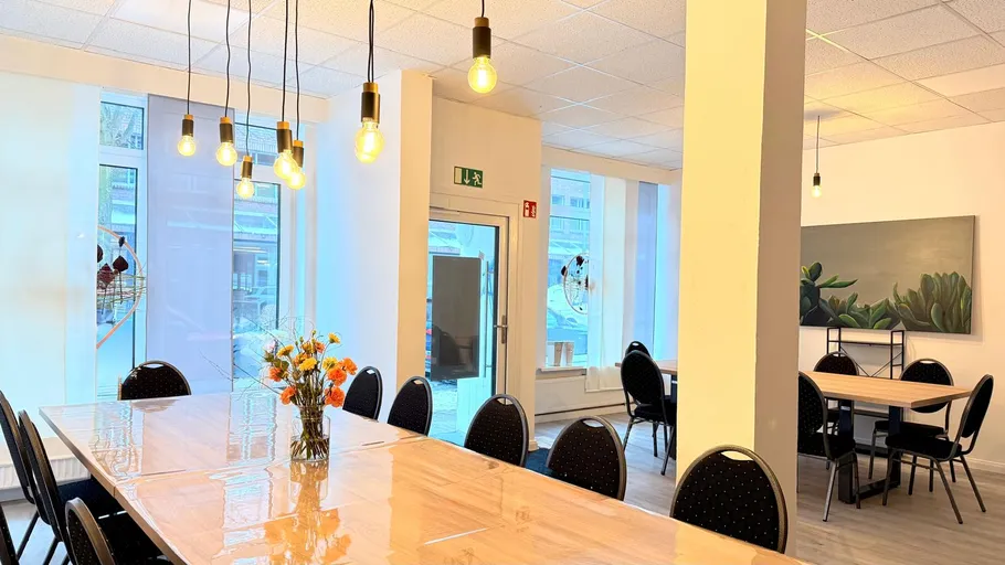 Atelierraum mit Tischen, Stühlen und Hängelampen.