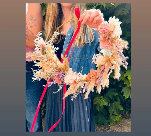 Person holding floral wreath with red ribbon.