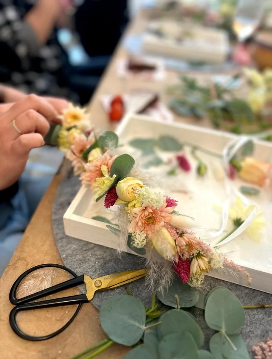 Person crafting floral arrangement at workshop table.