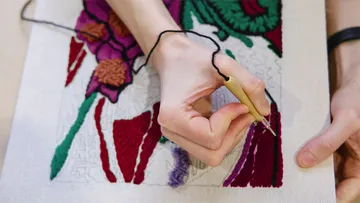 Hand embroidery on fabric with floral pattern.