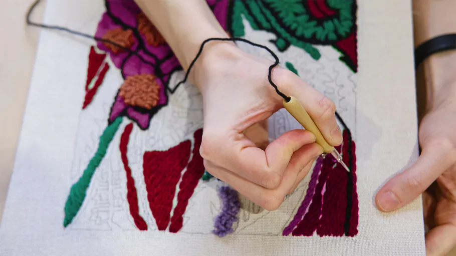 Hand embroidery on fabric with floral pattern.