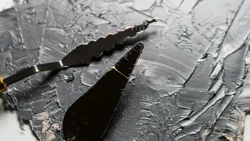 Two palette knives on textured gray paint.