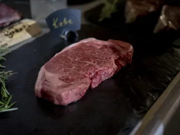 A piece of Kobe beef is lying on a black stone.