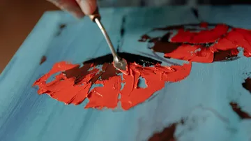 Hand using palette knife on abstract painting.