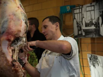Mann schneidet Fleisch von einem großen Tier; Arbeitsumgebung.