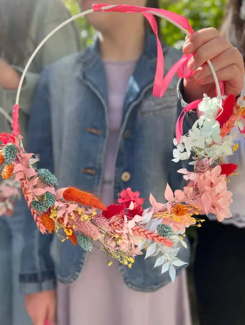 Person holding colorful floral wreath outdoors.
