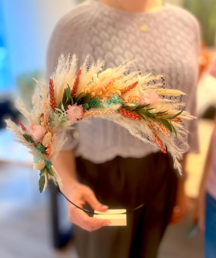 Woman holding floral headpiece indoors.