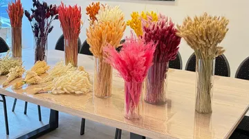 Colorful dried flowers in vases on wooden table.