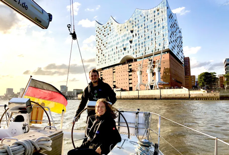 Two people sailing near modern building.