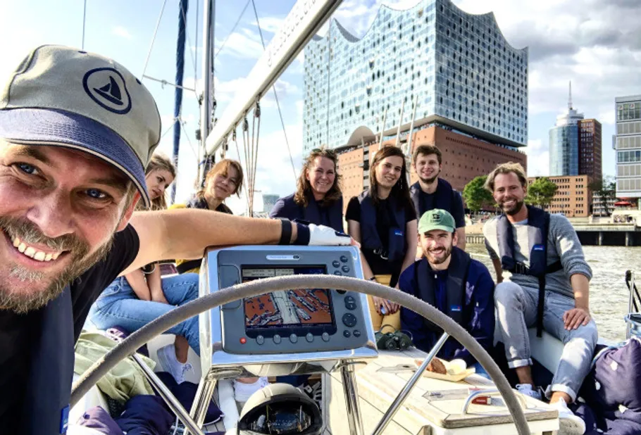 Group on a sailboat near urban waterfront.