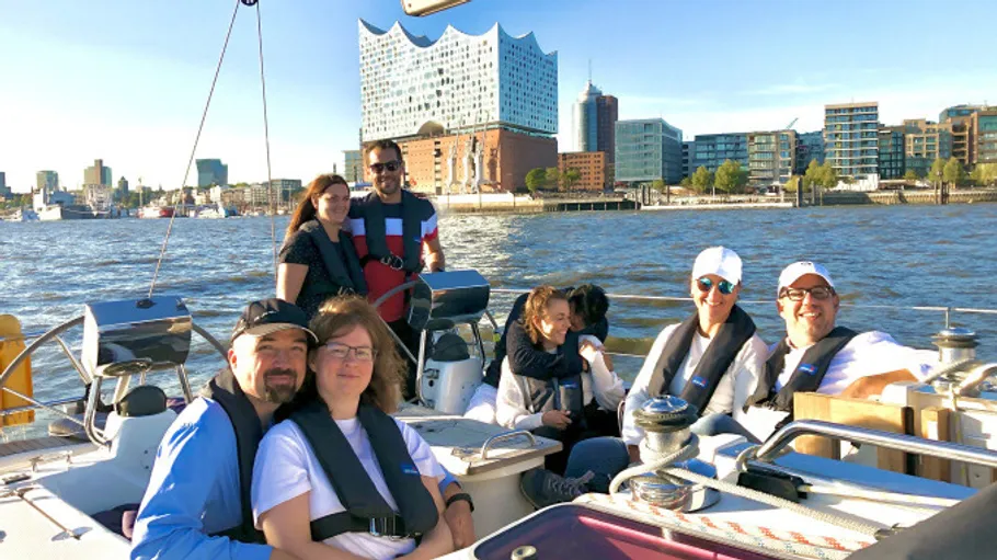 Group sailing on boat, city skyline in background.