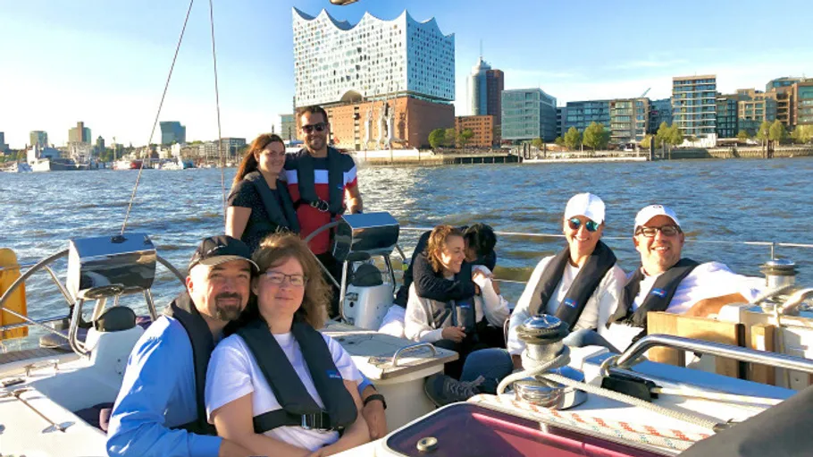 Gruppe segelt mit Stadtbild im Hintergrund.