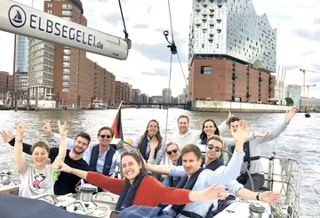 Gruppe Menschen segelt nahe einem modernen Gebäude.