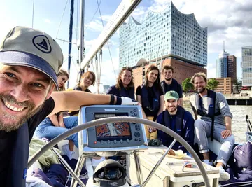 Group smiling on a boat with cityscape background.