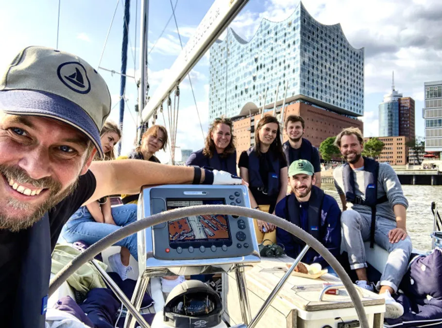 Gruppe lächelt auf einem Boot vor Stadtkulisse.