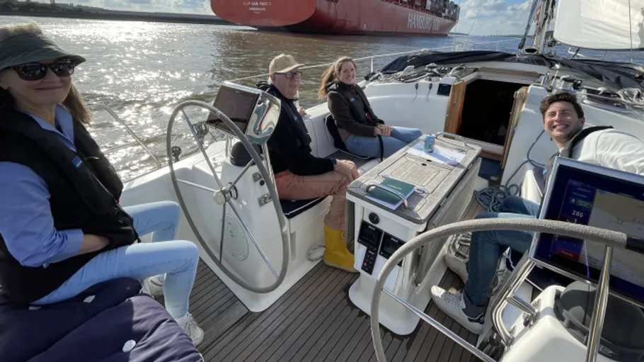 Four people relax on a sailboat, sunny day.