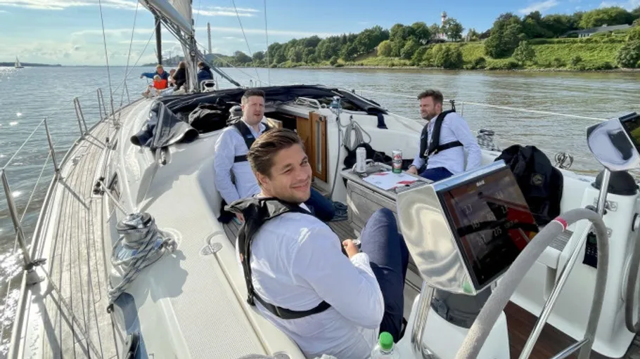 Three men sitting on a sailing boat deck.