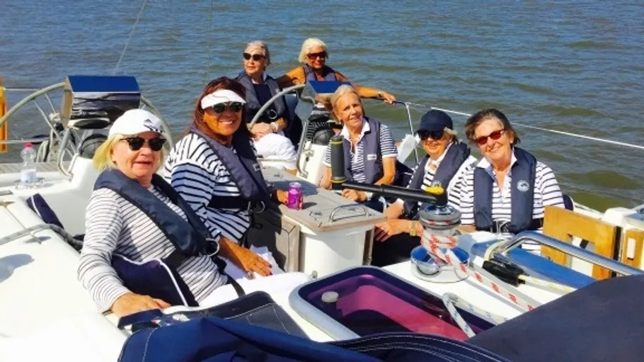 Group of women on a sailboat, smiling.