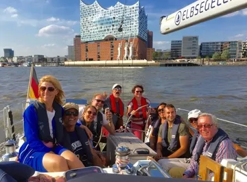 Gruppe segelt nahe modernem Gebäude, sonniger Tag.