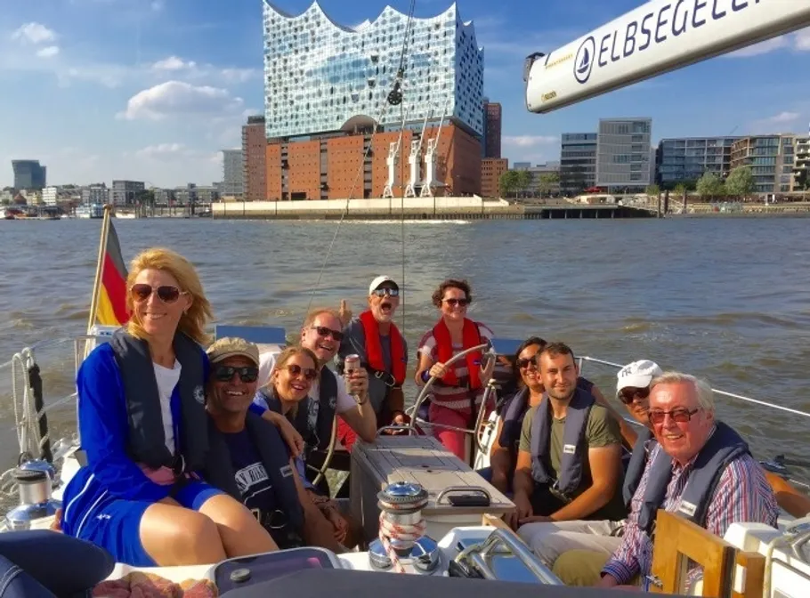 Group sailing near modern building, sunny day.