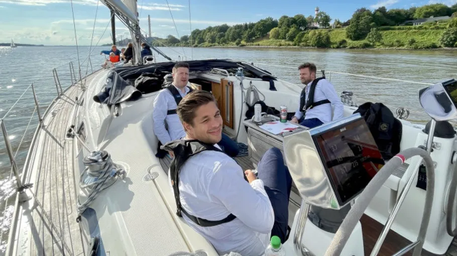 Männer entspannen auf Segelboot bei sonnigem Wetter.