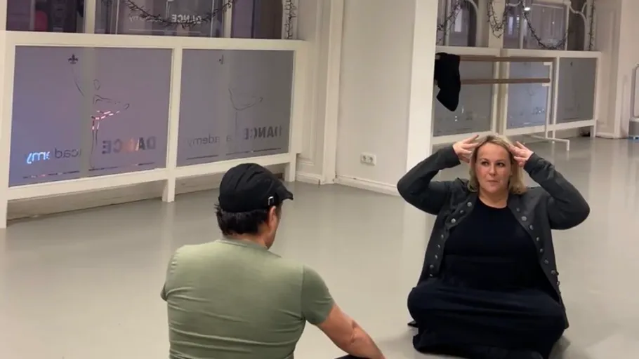 Zwei sitzende Personen, gestikulieren im Tanzstudio.