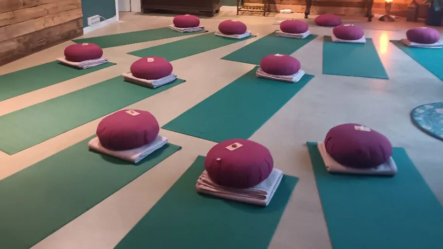Meditation cushions on mats in a studio.