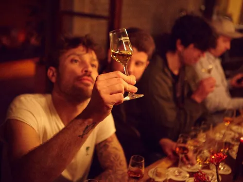 Man raises a glass while others sit in the bar.
