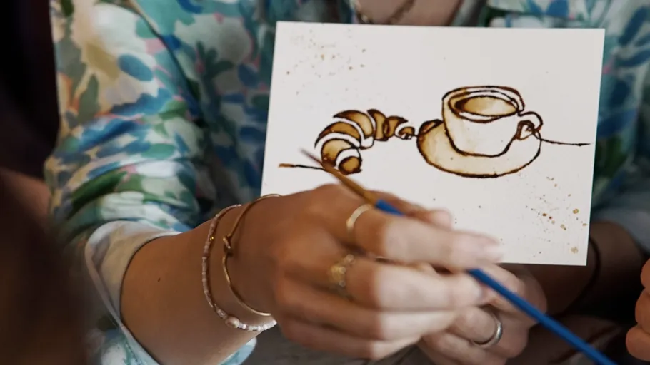 Person painting coffee and croissant picture.