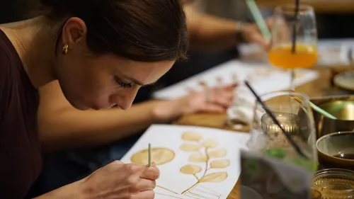 Woman painting leaves at a table.