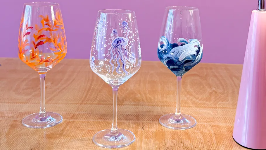 Three painted wine glasses on wooden table.