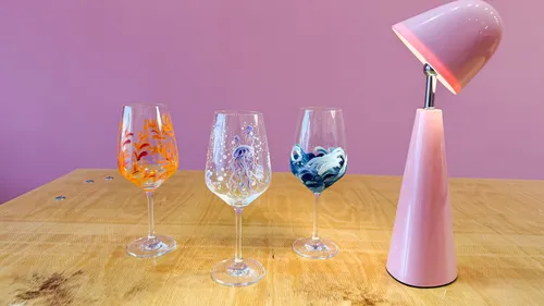 Painted glasses and pink lamp on table.