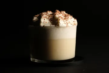 Cremiger Kaffee mit Schaum auf dunklem Hintergrund.